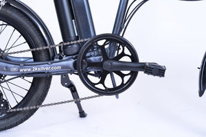 View of a pedal of a gray folding electric bike.