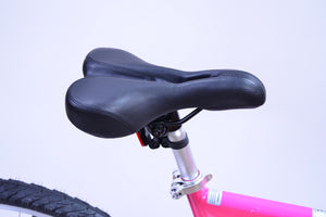 Black saddle on a silver seat post of a pink bicycle.