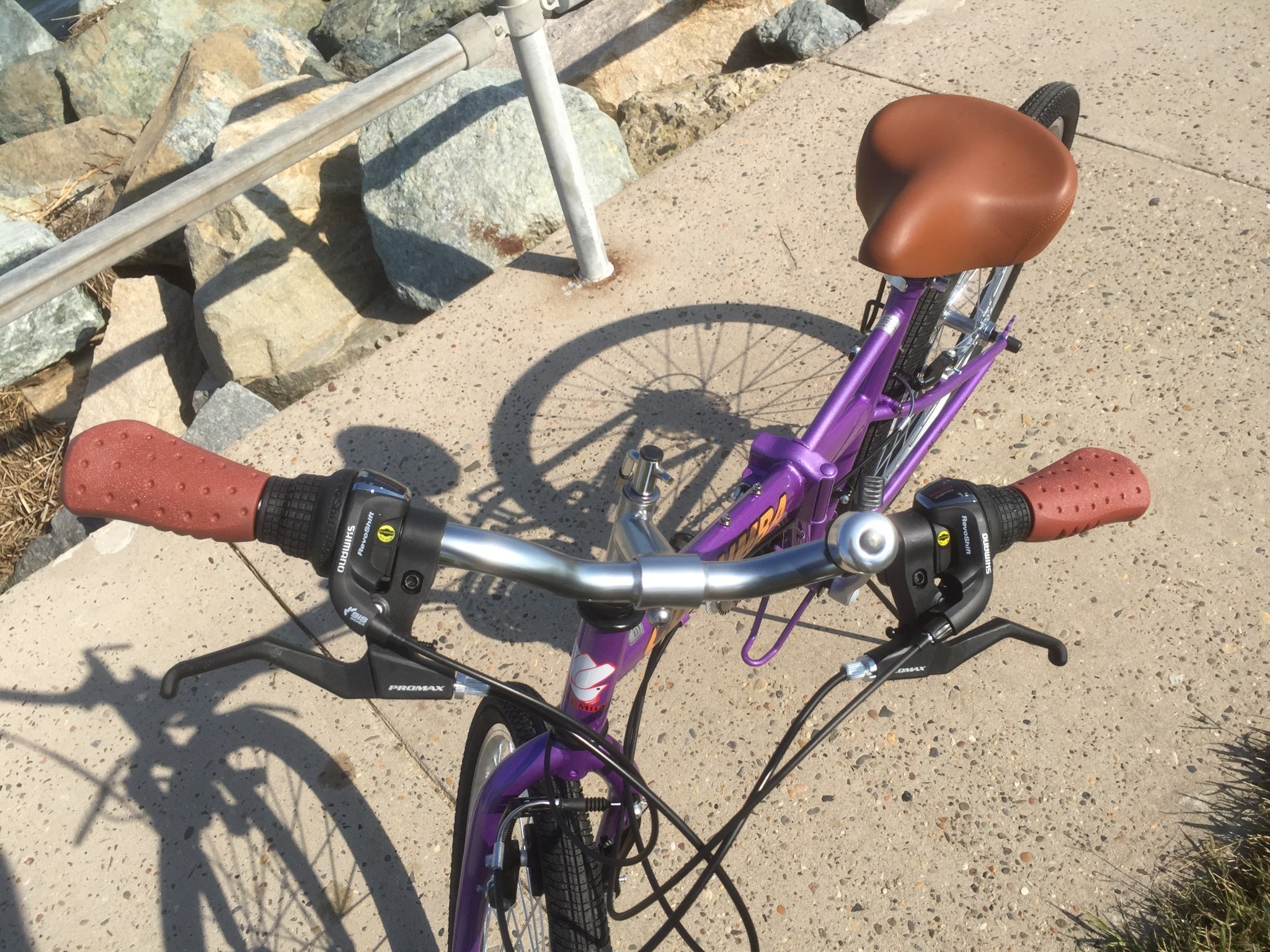 Handlebar of a purple folding bicycle.