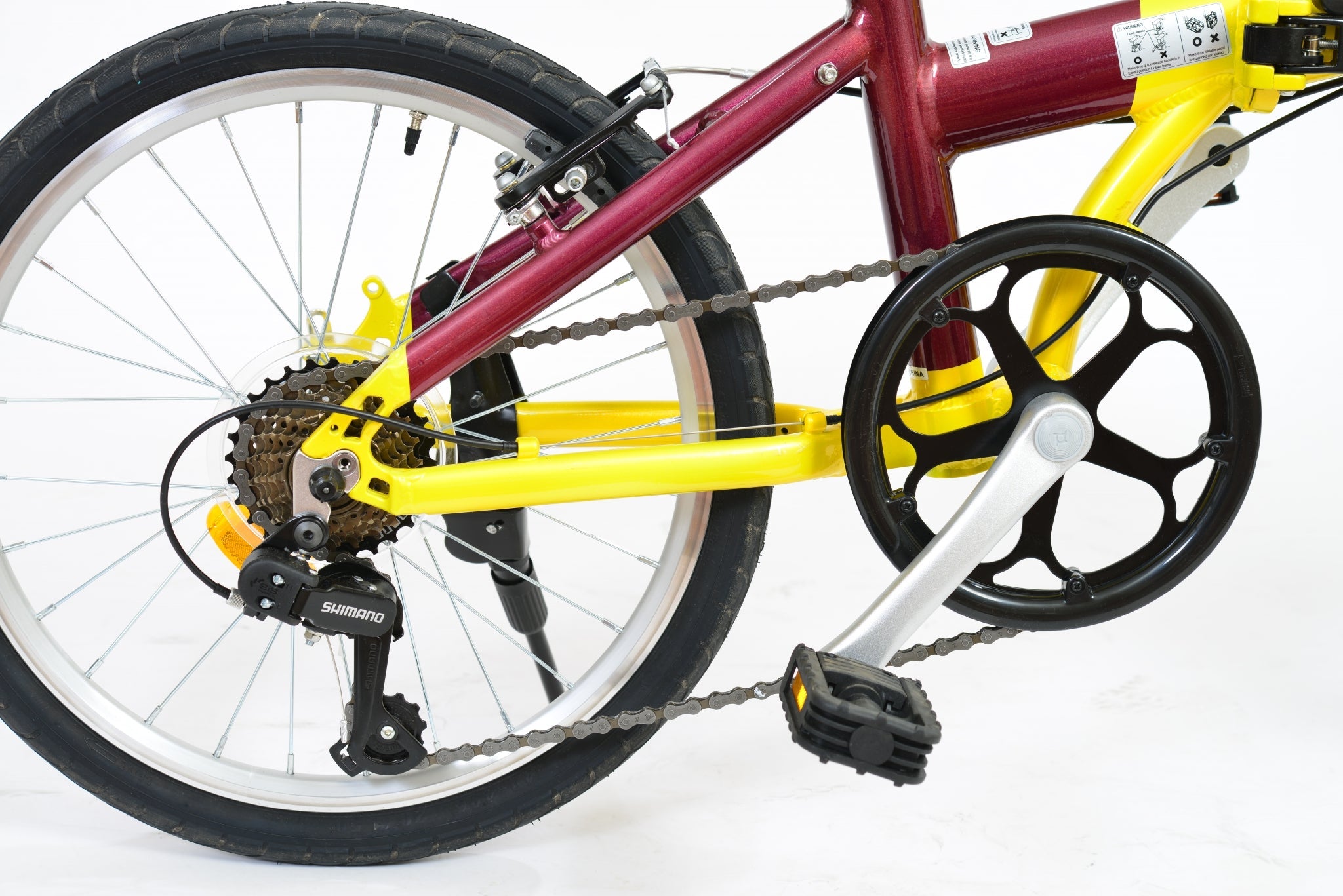Back wheel of a yellow and purple folding bicycle.