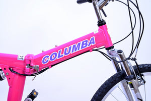 White and purple logo that reads "Columba" on the tube of a bright and vibrant pink folding bicycle.