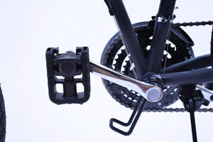 Foldable bike pedal in the folded position on a black bicycle. Also shown is the derailleur and the chains of the bike.