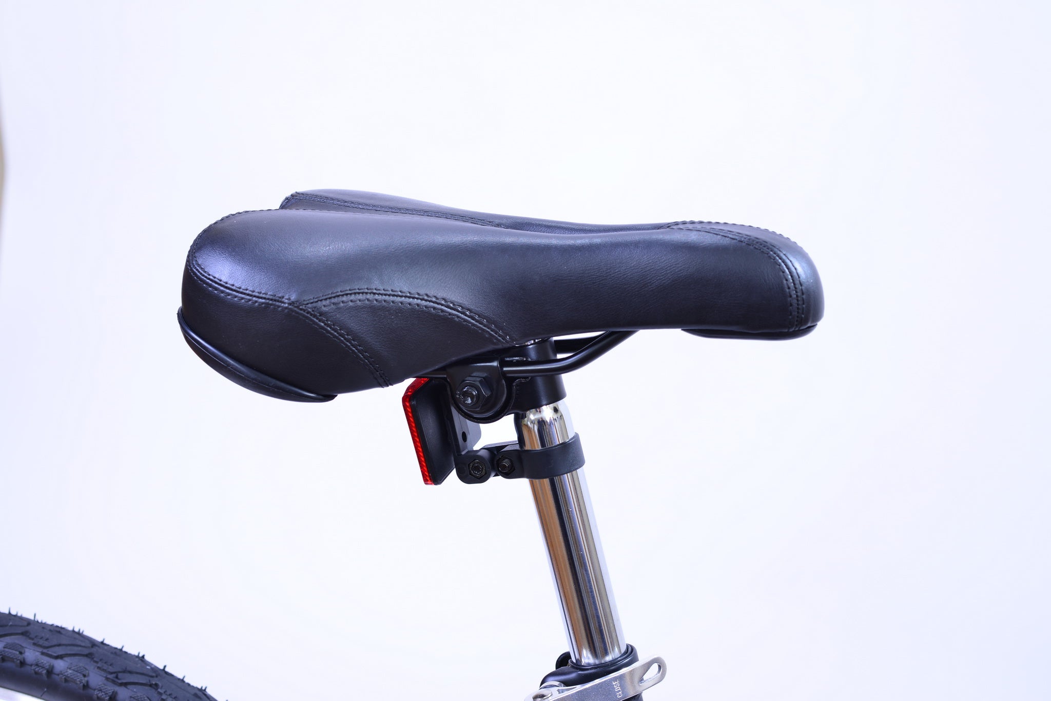 Black bike saddle on a silver seat post and with a red reflector in the back.