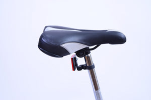 Black and silver bike saddle and seat post with red reflector.